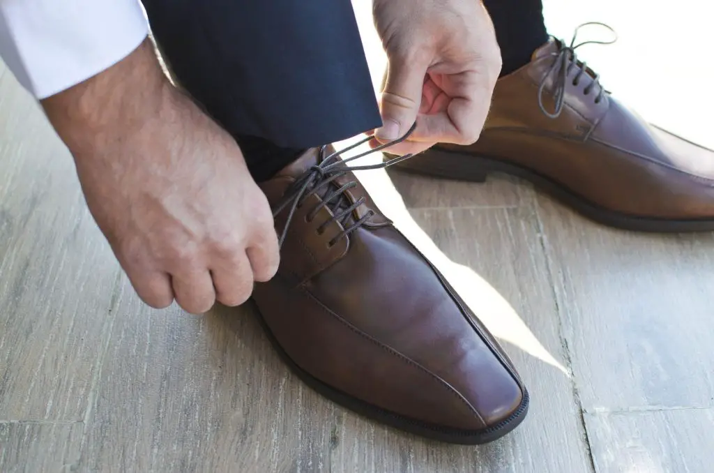 to become an actor you have to be committed like this businessman tying his crisp brown leather shoes getting ready to go to work
