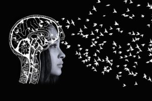 an asian woman is letting go of thoughts/beliefs she held to which are represented by tiny white birds leaving her brain