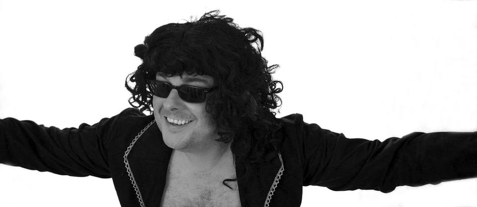 black and white image of a guy with curly hair and sunglasses smiling