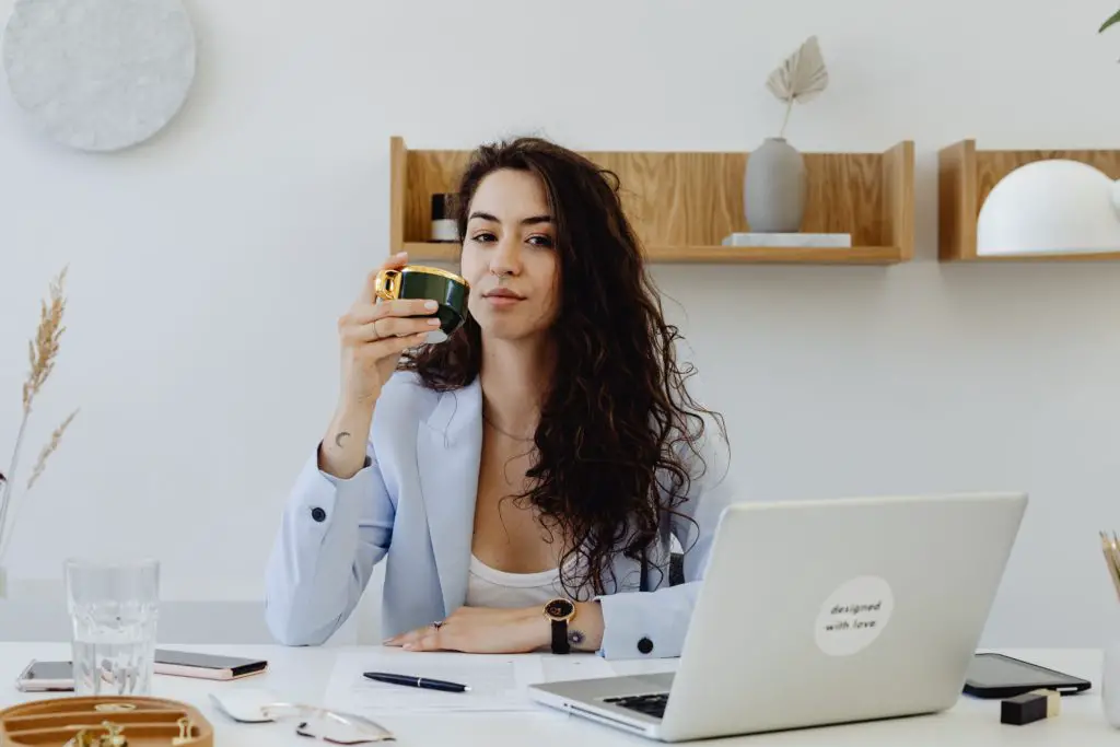 women drinking coffee infront of her laptop